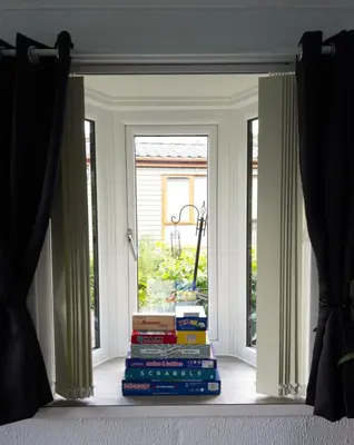 a stack of books in front of a window at Lodge by the Lake - Lake District - Hot Tub in Bassenthwaite