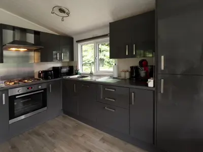 a kitchen with black cabinets and a stove top oven at Lodge by the Lake - Lake District - Hot Tub in Bassenthwaite