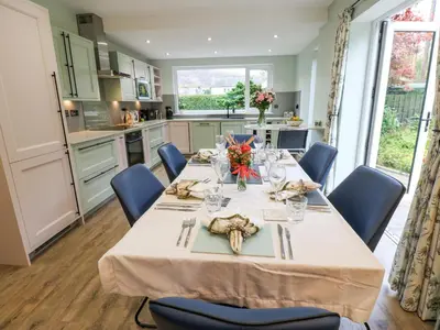 a dining room with a table with blue chairs at Esk Brae in Langholm