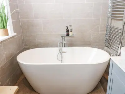 a white bath tub in a bathroom with tiles at Esk Brae in Langholm
