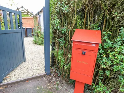 a red mailbox sitting in front of a fence at Esk Brae in Langholm