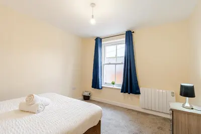 a bedroom with a bed and a window with blue curtains at John Dalton House in Cockermouth