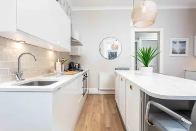 a kitchen with white cabinets and a sink at The Bradshaw in Prestwick