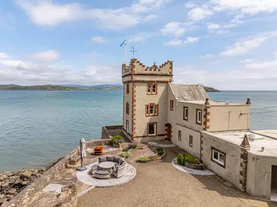 an old castle in the middle of a body of water at Balcary Tower in Castle Douglas