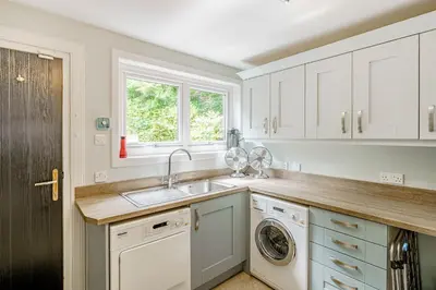 a kitchen with white cabinets and a sink at Balcary Tower in Castle Douglas
