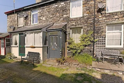 a stone house with a green door and a bench at The Escape in Portinscale