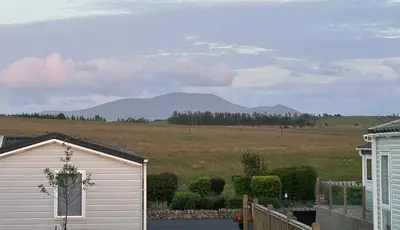 a white garage with mountains in the background at Ralfgus 16 Forest Views caravan Park,Moota in Plumbland