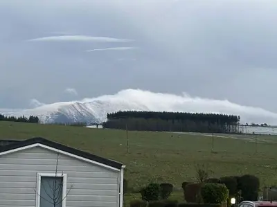 a house in a field with a snow covered mountain at Ralfgus 16 Forest Views caravan Park,Moota in Plumbland