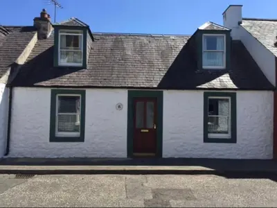 a white house with a red door on a street at Lazy Days in Moffat