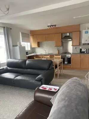 a living room with a black leather couch and a kitchen at Spacious Property For Hols Base & Contractors Long or Short Stays C2C Western Lakes in Cleator Moor