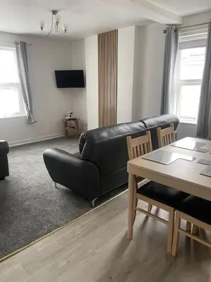 a living room with a black leather couch and a table at Spacious Property For Hols Base & Contractors Long or Short Stays C2C Western Lakes in Cleator Moor