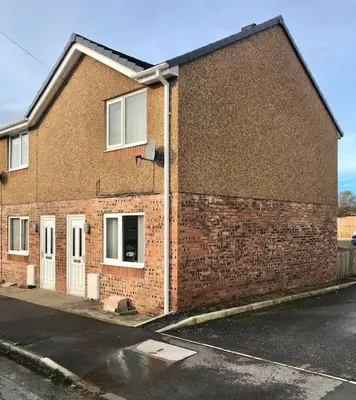 a brick building with white doors on a street at CosyHouse2 Private Parking Base for Lake District and Sellafield in Cleator Moor