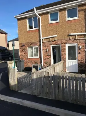 a brick house with a wooden fence in front of it at CosyHouse2 Private Parking Base for Lake District and Sellafield in Cleator Moor