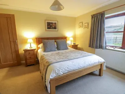 a bedroom with a bed with blue pillows and a window at The Stables at Daldorch in Mauchline