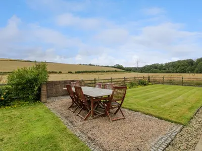 a table and chairs on a patio with a field at The Stables at Daldorch in Mauchline