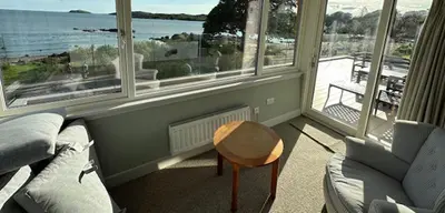 a living room with a couch and a table and windows at Whitegates in Rockcliffe