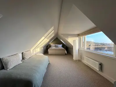 a attic bedroom with a bed and a large window at Whitegates in Rockcliffe