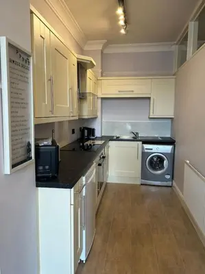 a kitchen with white cabinets and a washer and dryer at 10 Thurnams House in Carlisle