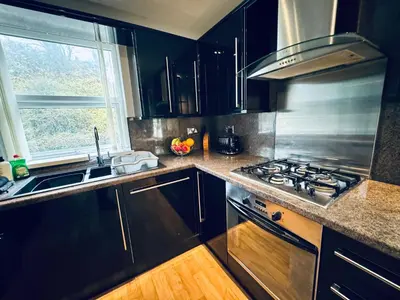 a kitchen with black cabinets and a stove and a window at New Road Apartment - 2 Bedrooms - Sleeps 3 in Whitehaven