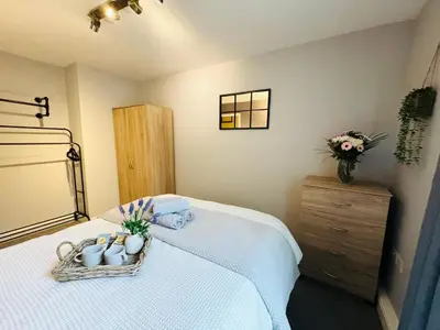 a bedroom with a bed with towels and cups and a dresser at New Road Apartment - 2 Bedrooms - Sleeps 3 in Whitehaven