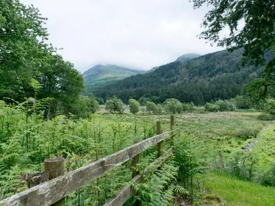 a fence in a field with mountains in the background at YHA Ennerdale in Buttermere