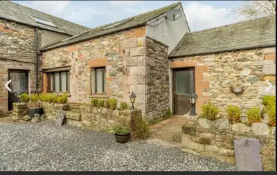 a stone house with a courtyard in front of it at Troutbeck Inn Cottages in Troutbeck