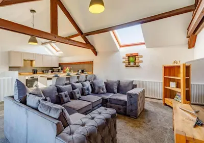 a living room with a large couch and a kitchen at Troutbeck Inn Cottages in Troutbeck