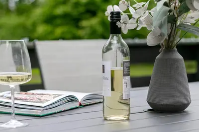 a bottle of wine and a vase with a book at Newsham Lodge in Ellonby