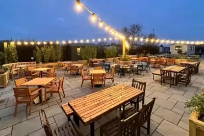 an outdoor patio with tables and chairs and lights at The Cosy Hedgerow in Port Carlisle