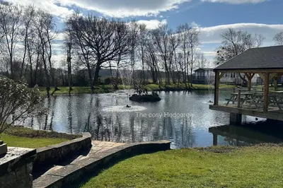 a pond with a gazebo next to a park at The Cosy Hedgerow in Port Carlisle