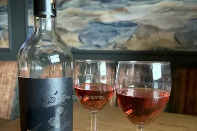 two wine glasses sitting next to a bottle of wine at The Cosy Hedgerow in Port Carlisle