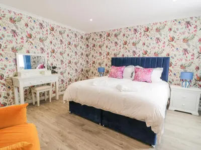 a bedroom with a bed with floral wallpaper at Waterside Lodge in Lockerbie