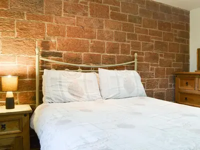 a bed in a bedroom with a brick wall at Meadow Lodge-E4105 in Aspatria