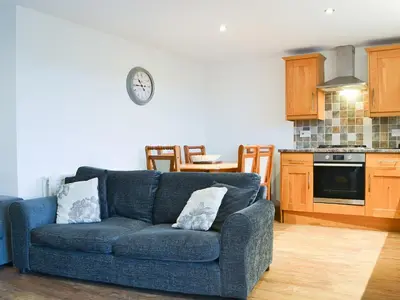 a living room with a blue couch and a kitchen at Meadow Lodge-E4105 in Aspatria
