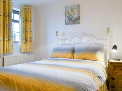 a bedroom with a bed with yellow curtains at Meadow Lodge-E4105 in Aspatria