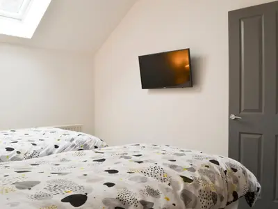 a bed with a comforter with a tv on a wall at Sunset View-E4107A in Aspatria
