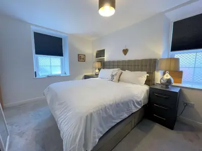 a bedroom with a large bed and two windows at Stunning Cosy Cottage in Historic Moffat - Pass the Keys in Moffat
