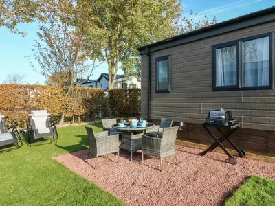 a backyard with a table and chairs and a grill at Brocklebank Lodge, 35 in Carlisle