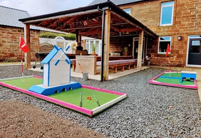 two miniature golf courses in a yard in front of a house at Family and dog friendly stunning barn conversion in Tarbolton