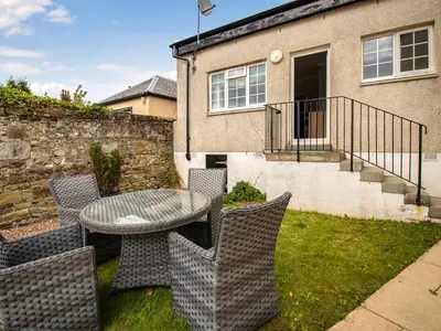 a patio with a table and chairs in front of a house at The Loans Inn Cottage in Loans