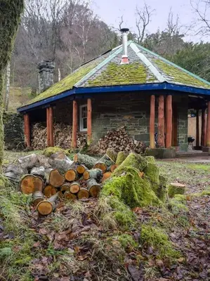 a pile of logs in front of a house at The Dairy - Patterdale Hall in Penrith