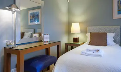 a bedroom with a bed with a desk and a mirror at Blencathra in Keswick