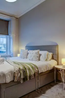 a bedroom with a large bed with a blue wall at The Fullarton - Coorie Doon Stays in Troon