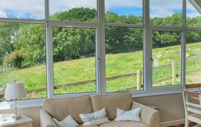 a living room with large windows looking out onto a green field at Bardristane Forge in Gatehouse of Fleet