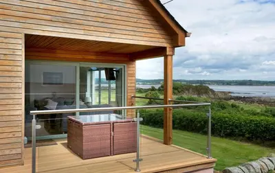a house with a deck with a view of the water at Curlew Cottage in Gatehouse of Fleet