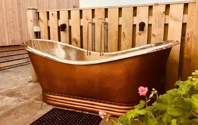 a wooden bath tub sitting next to a fence at Little Beach in Gatehouse of Fleet