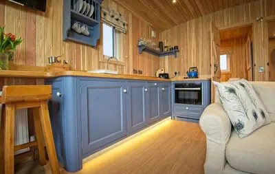 a kitchen with blue cabinets and a couch in a room at Little Oak in Gatehouse of Fleet
