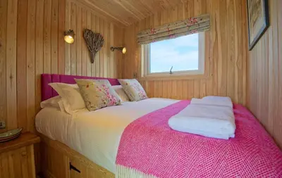 a bedroom with a bed with a pink blanket at Little Willow in Gatehouse of Fleet