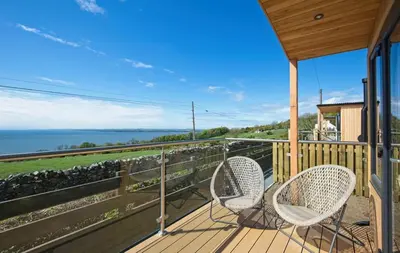 a porch with two chairs and a view of the ocean at Little Willow in Gatehouse of Fleet