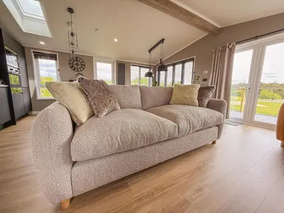 a brown couch in a living room with windows at Dogwood Lodge in Bassenthwaite